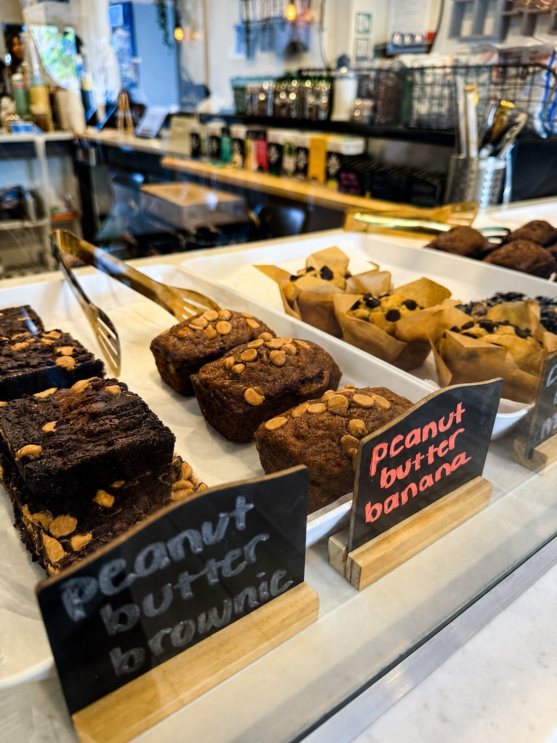 The pastry case with handwritten signs for peanut butter brownies and peanut butter banana loaves